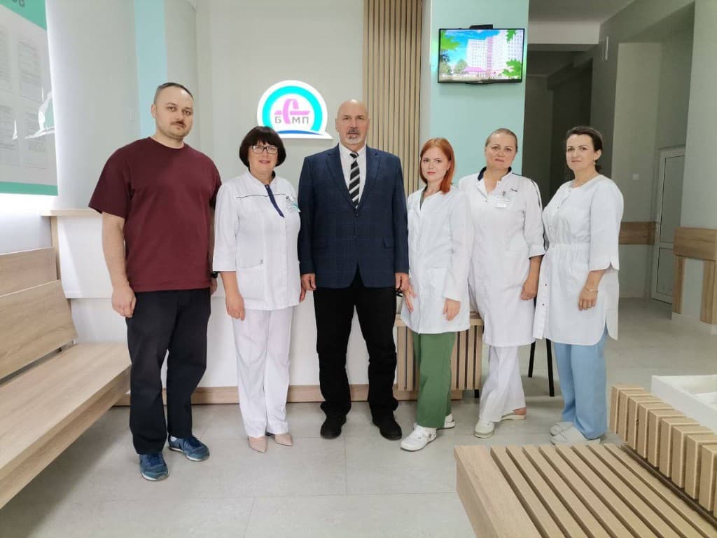 Коллектив медицинской организации и администрации в современном холле БСМП с фирменным логотипом учреждения